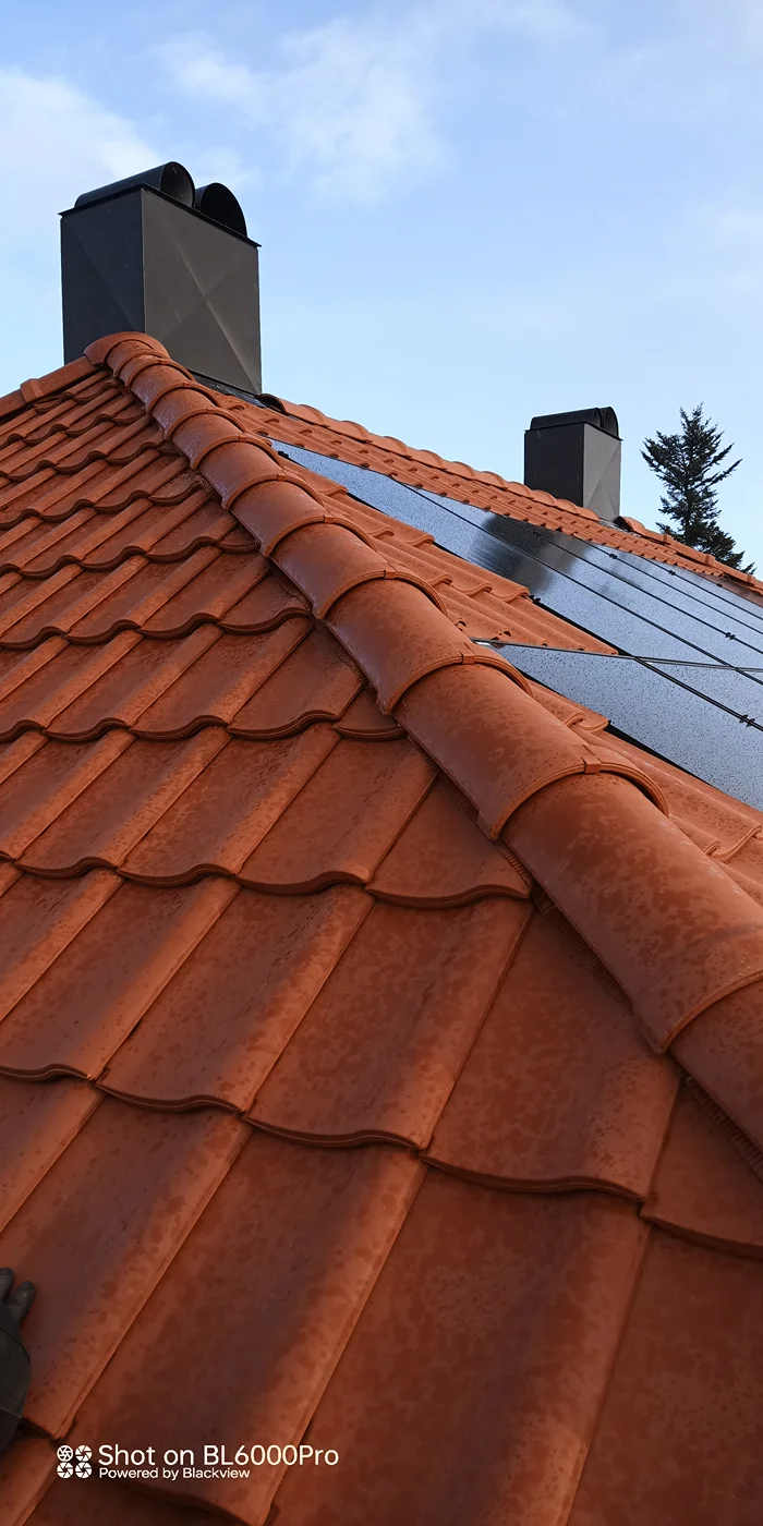 Red tiled roof with chimneys and solar panels