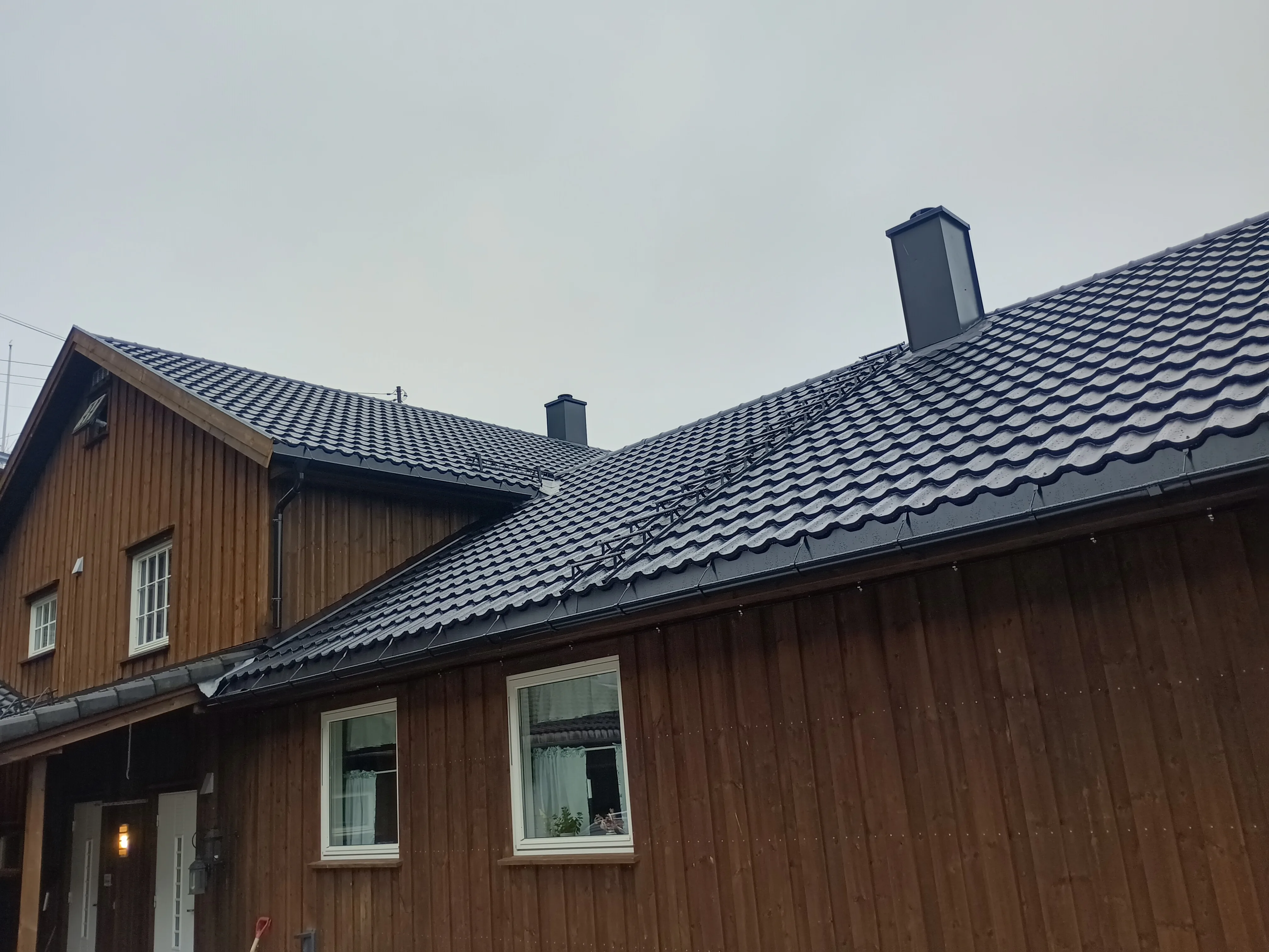 Takstein på skråtaket av en hytte med to pipeløp
