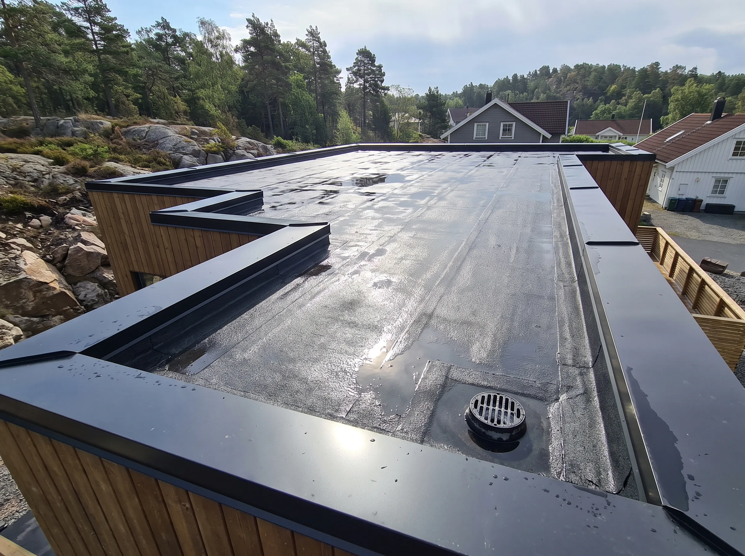 Flatt tak med moderne takmembran på en bygning i et naturskjønt område