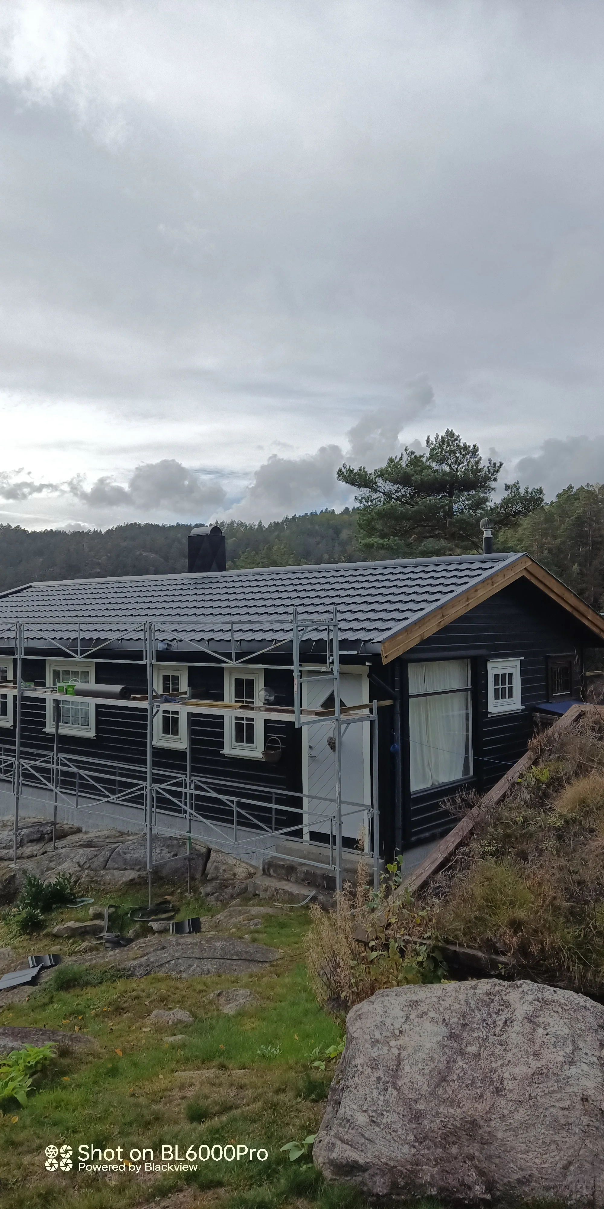 Hytte med nytt tak av takstein og stillas rundt