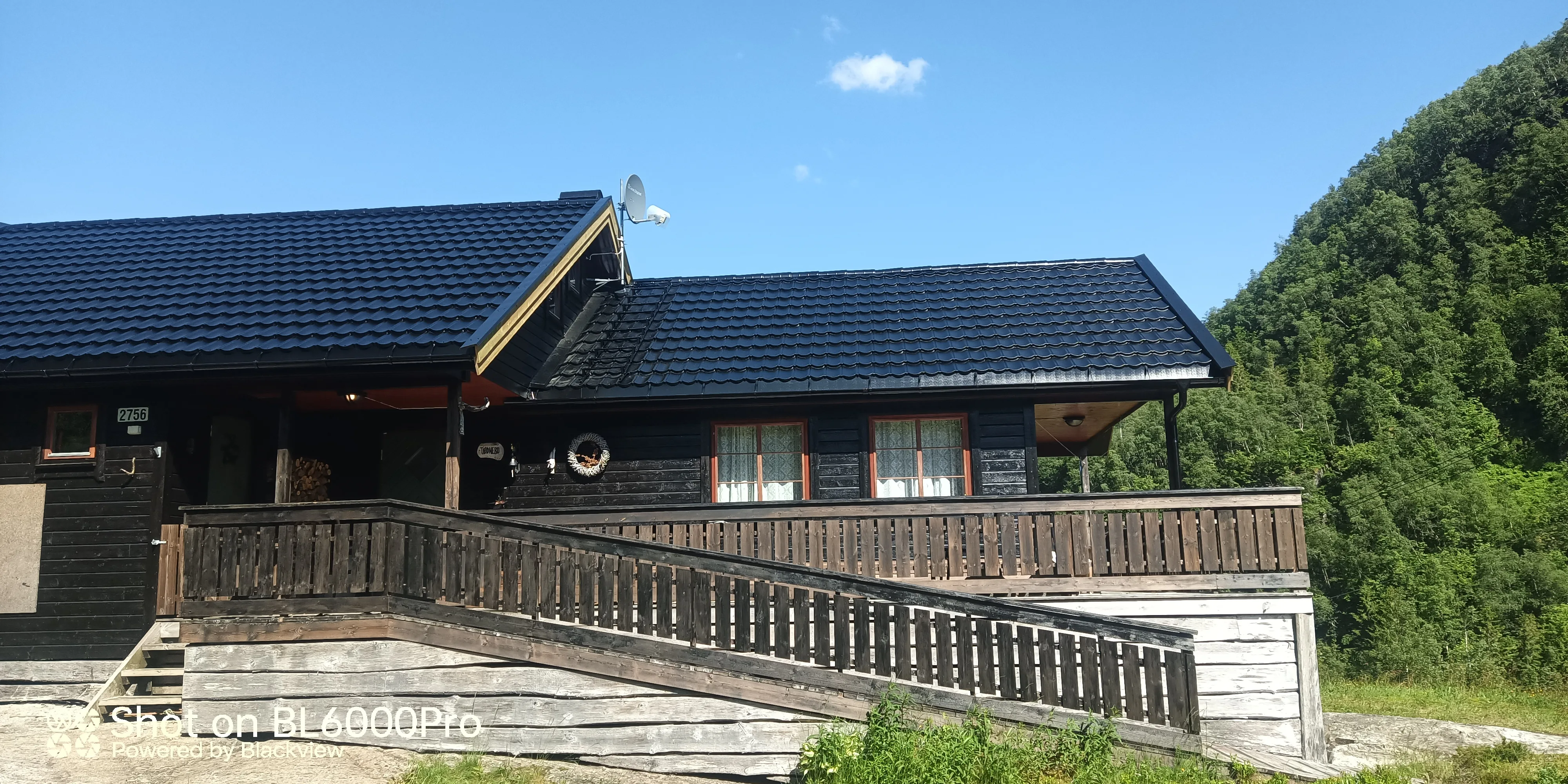 Hytte med skråtak og treterrasse i naturskjønt område