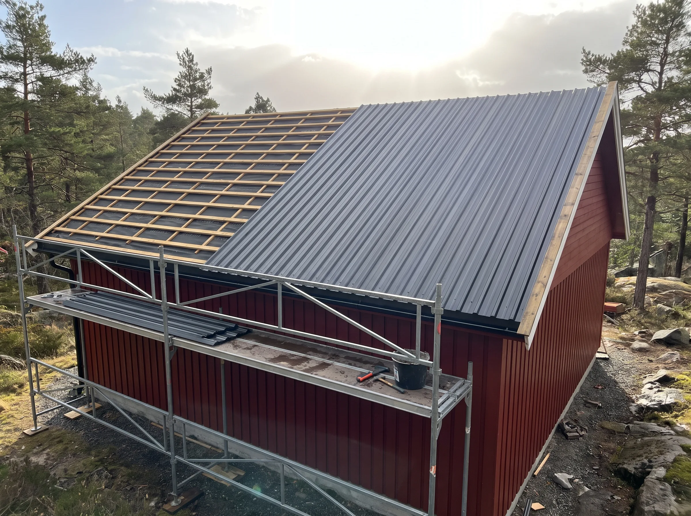 Montering av ståltak på en hytte, med takrenner og stillaser i forgrunnen