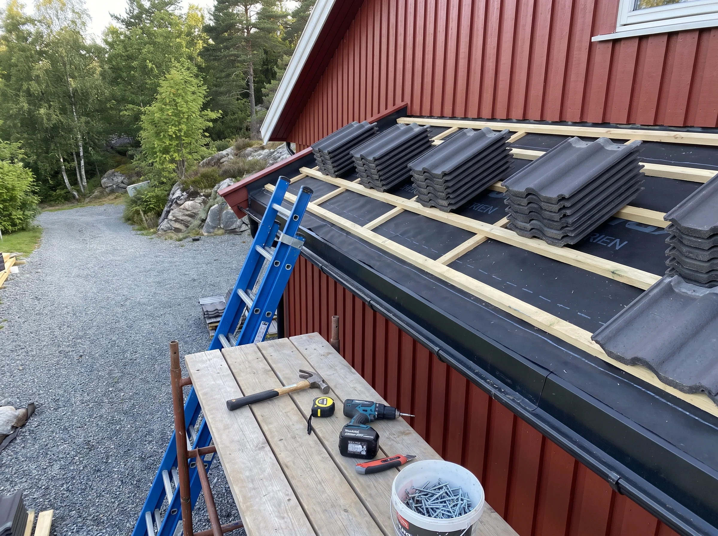 Takomlegging med takstein på pulttak, verktøy og materialer synlige