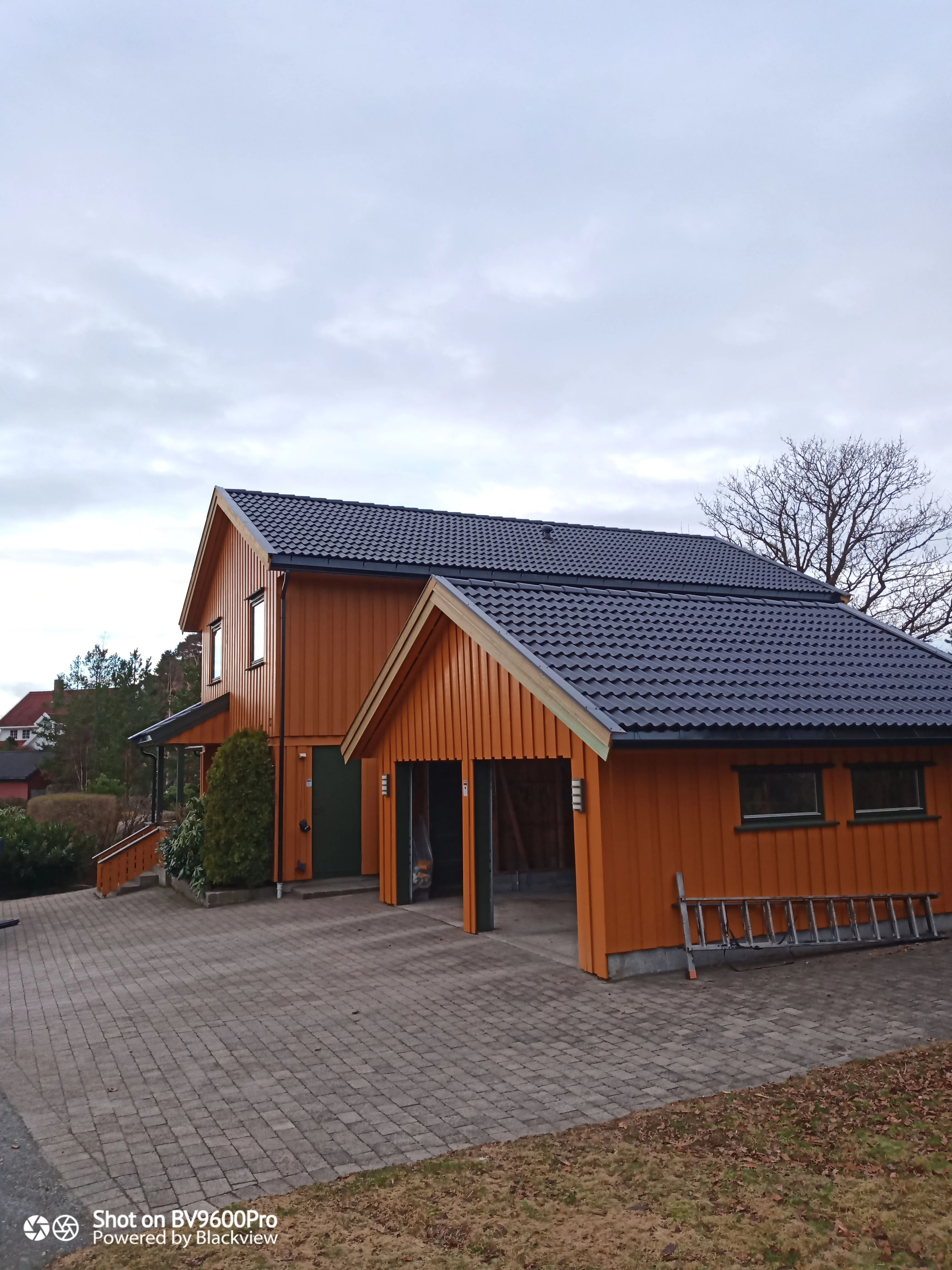 En moderne husfasade med skråtak dekket av takstein og en garasje foran